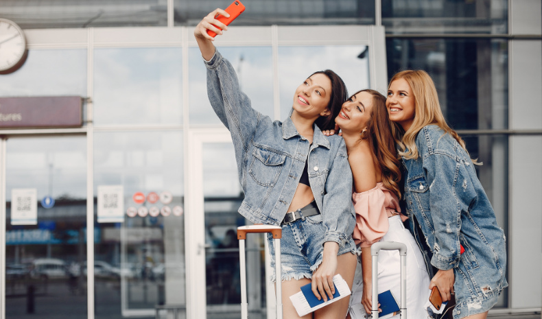 Young women taking selfie photos outside airport