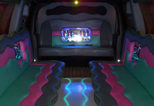 View of rear seating area inside limousine with bar area and mood lighting
