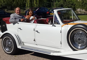 Bride and groom sit in car with lowered roof